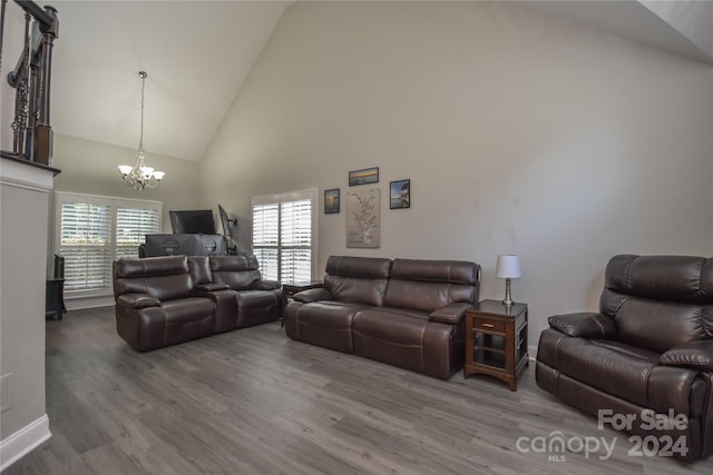 living room with hardwood / wood-style flooring, high vaulted ceiling, and a notable chandelier