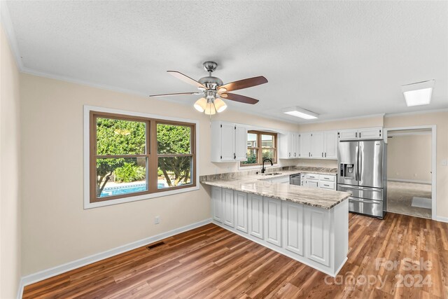 kitchen with kitchen peninsula, white cabinetry, stainless steel appliances, and dark wood-type flooring