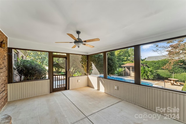 unfurnished sunroom featuring ceiling fan and a wealth of natural light