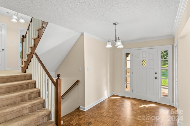 entryway featuring ornamental molding, parquet flooring, a notable chandelier, and a textured ceiling