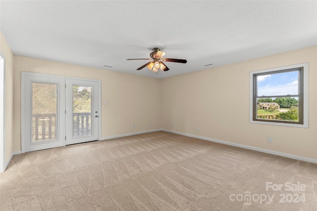 spare room with ceiling fan, light colored carpet, and a wealth of natural light