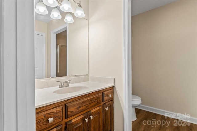 bathroom with wood-type flooring, vanity, toilet, and a shower with door