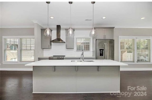 kitchen with sink, wall chimney range hood, decorative light fixtures, gray cabinets, and appliances with stainless steel finishes