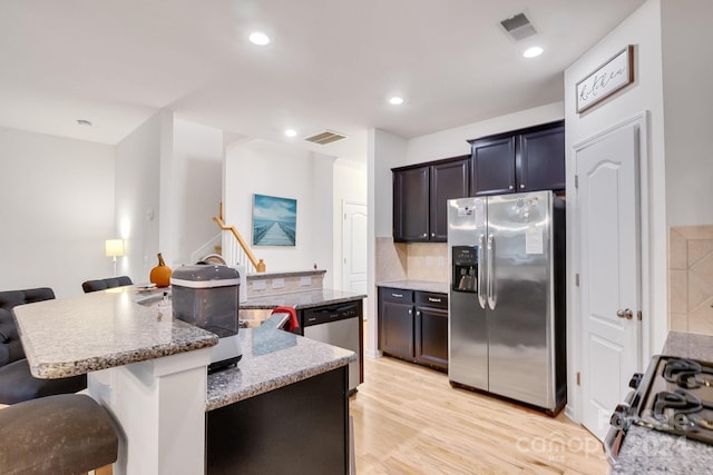 kitchen featuring appliances with stainless steel finishes, a breakfast bar area, and an island with sink