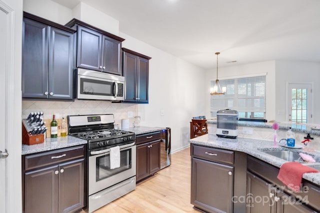 kitchen with decorative backsplash, dark brown cabinets, appliances with stainless steel finishes, light hardwood / wood-style flooring, and pendant lighting