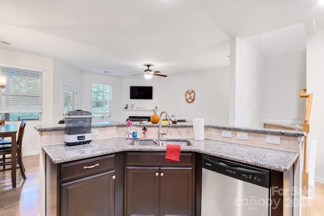 kitchen featuring dark brown cabinets, light stone countertops, stainless steel dishwasher, light wood-type flooring, and sink