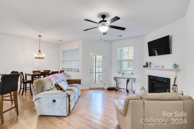 living room with ceiling fan with notable chandelier and light wood-type flooring