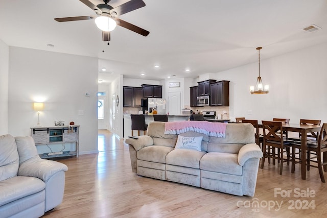 living room with light hardwood / wood-style flooring and ceiling fan with notable chandelier