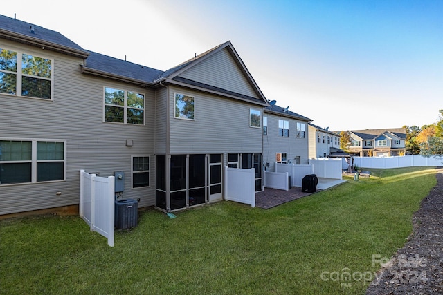 rear view of house with central AC and a yard