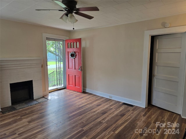 unfurnished living room with a brick fireplace, crown molding, dark hardwood / wood-style flooring, and ceiling fan