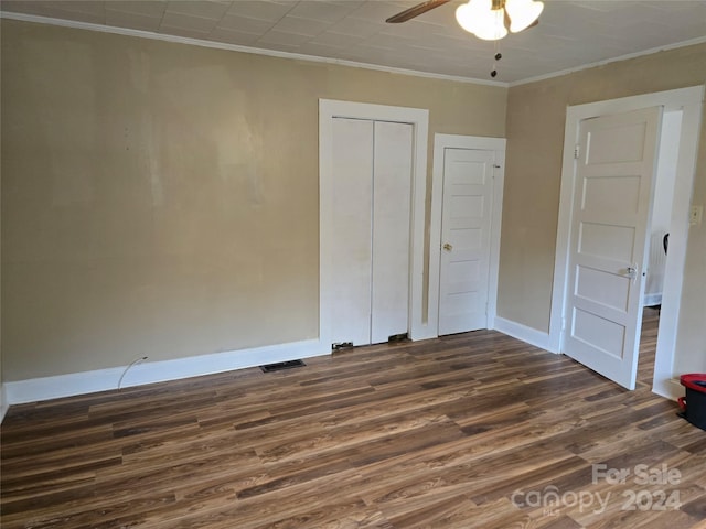 unfurnished bedroom with ornamental molding, a closet, ceiling fan, and dark wood-type flooring