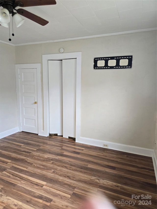 unfurnished bedroom featuring ornamental molding, dark hardwood / wood-style flooring, ceiling fan, and a closet