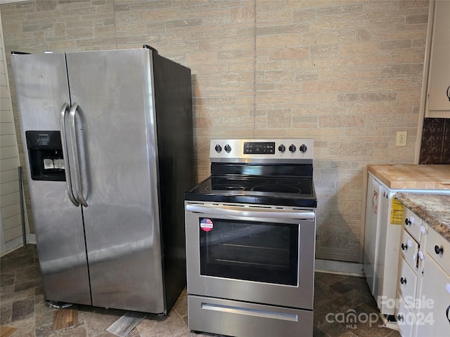 kitchen with stainless steel appliances, tile walls, and white cabinetry