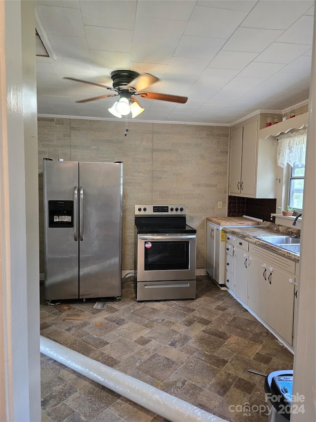 kitchen with appliances with stainless steel finishes, tile walls, sink, and ceiling fan