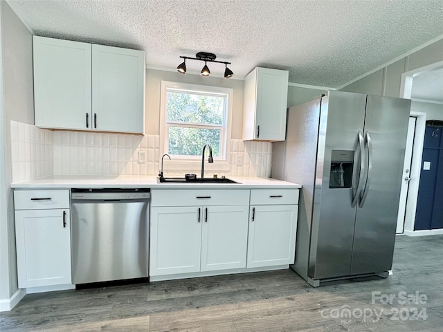 kitchen with white cabinetry, tasteful backsplash, stainless steel appliances, hardwood / wood-style floors, and sink