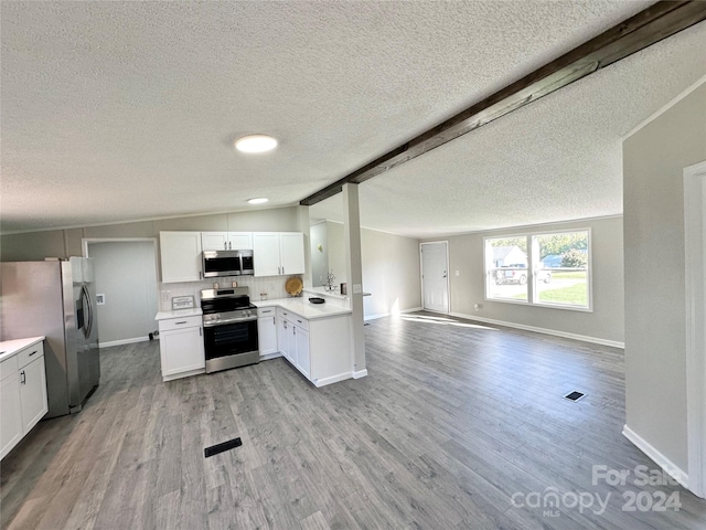 kitchen with vaulted ceiling with beams, a textured ceiling, light hardwood / wood-style flooring, white cabinetry, and stainless steel appliances