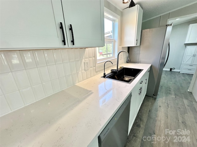 kitchen with white cabinets, sink, stainless steel dishwasher, hardwood / wood-style flooring, and light stone countertops