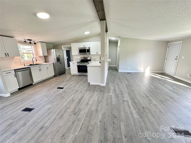 kitchen featuring sink, white cabinetry, vaulted ceiling, light hardwood / wood-style flooring, and stainless steel appliances