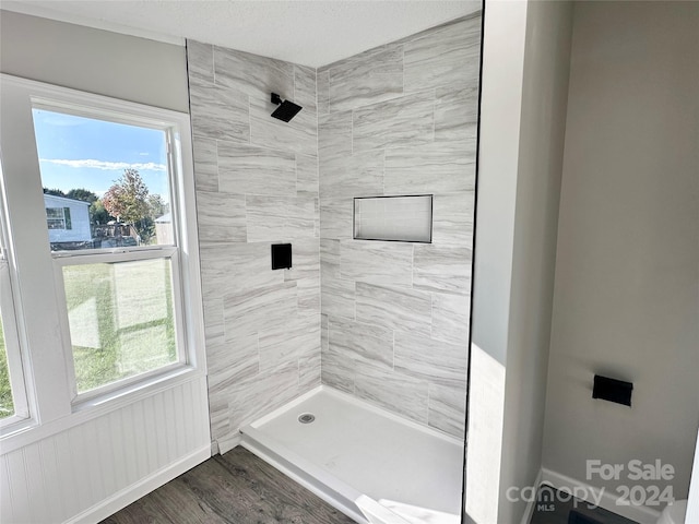 bathroom featuring a tile shower, wood-type flooring, and a healthy amount of sunlight