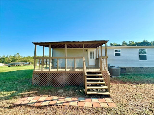 rear view of house with cooling unit, a deck, and a yard