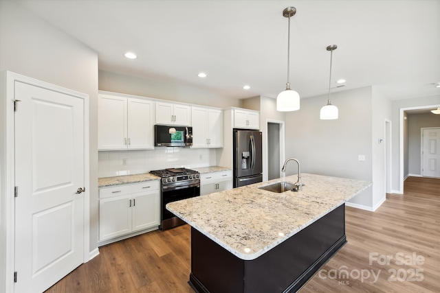 kitchen featuring an island with sink, appliances with stainless steel finishes, sink, and white cabinetry