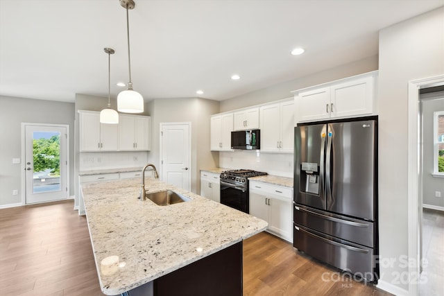 kitchen featuring decorative backsplash, white cabinetry, appliances with stainless steel finishes, and a kitchen island with sink