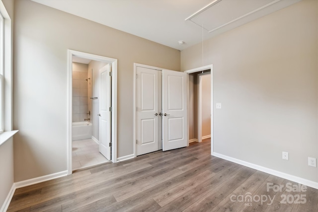 unfurnished bedroom with light wood-type flooring and ensuite bathroom