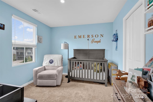 carpeted bedroom featuring visible vents, baseboards, and a nursery area