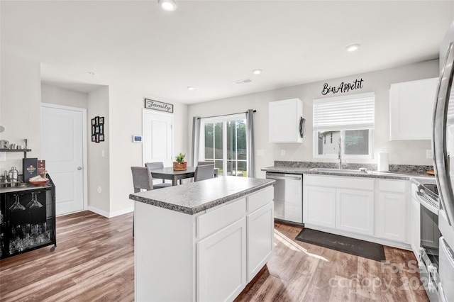 kitchen featuring visible vents, a center island, light wood-style flooring, stainless steel appliances, and a sink