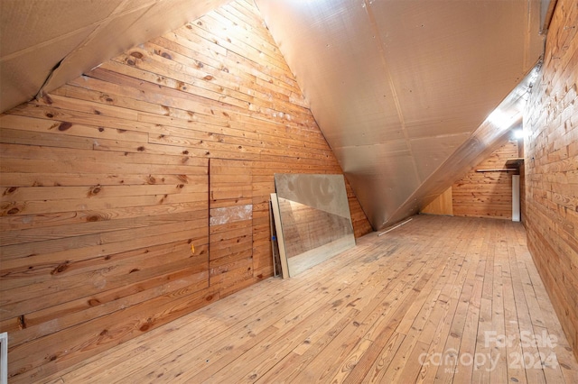 bonus room with wood walls, lofted ceiling, and light hardwood / wood-style flooring