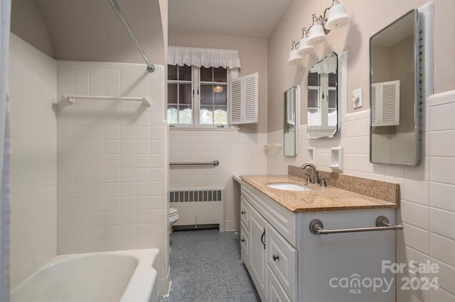 full bathroom with tiled shower / bath, vanity, radiator heating unit, toilet, and tile walls