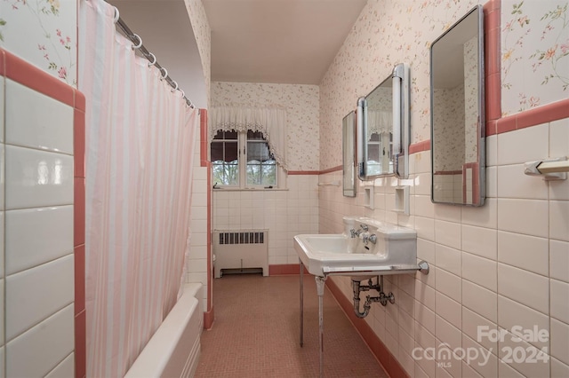 bathroom with tile patterned flooring, sink, shower / tub combo, radiator heating unit, and tile walls