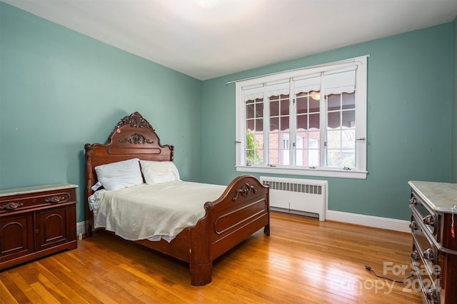 bedroom featuring radiator and light hardwood / wood-style floors