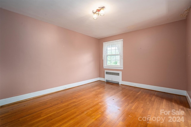 empty room with radiator and hardwood / wood-style floors