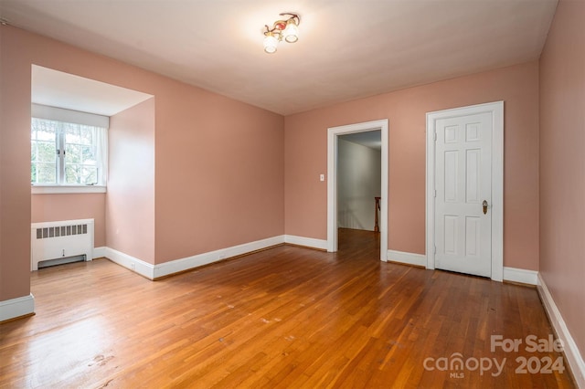 unfurnished room featuring hardwood / wood-style flooring and radiator