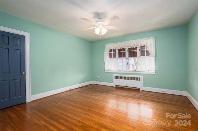 unfurnished room with hardwood / wood-style floors, radiator, and ceiling fan