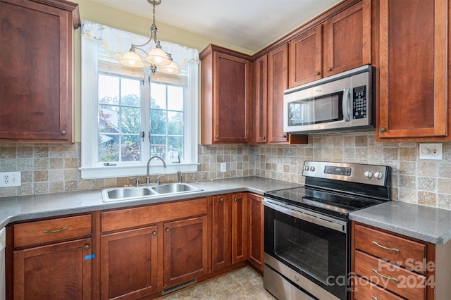 kitchen featuring appliances with stainless steel finishes, decorative light fixtures, sink, and tasteful backsplash