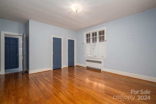 unfurnished room featuring radiator and hardwood / wood-style flooring