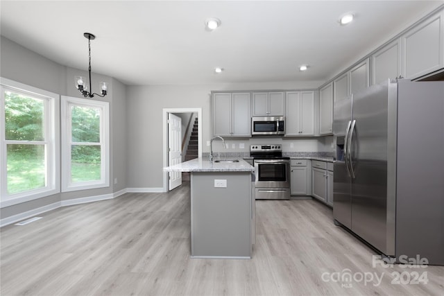 kitchen featuring gray cabinetry, light wood-type flooring, stainless steel appliances, and pendant lighting