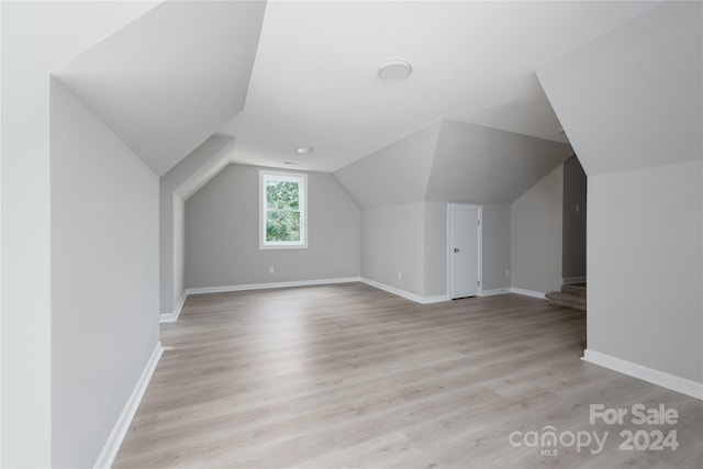 additional living space with vaulted ceiling and light hardwood / wood-style flooring