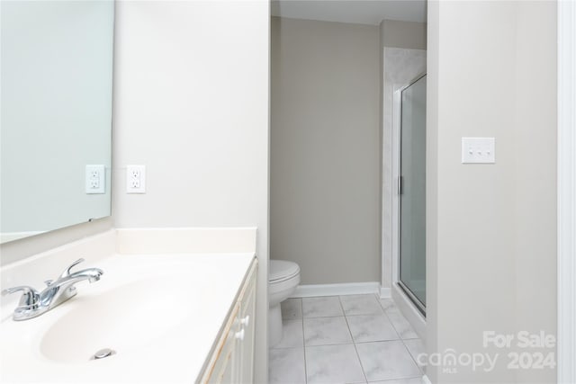 bathroom with vanity, a shower with shower door, toilet, and tile patterned flooring