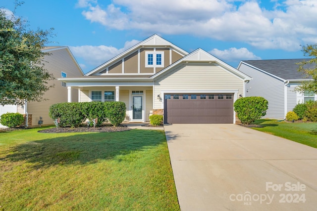 view of front of property with a front lawn, covered porch, and a garage