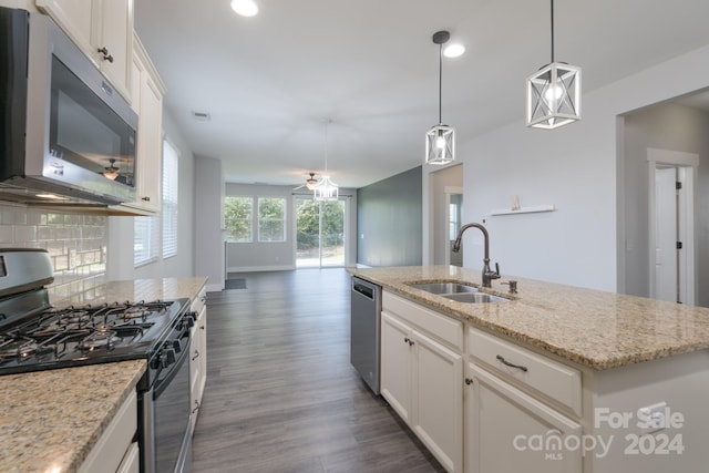 kitchen with a kitchen island with sink, sink, white cabinets, appliances with stainless steel finishes, and decorative light fixtures