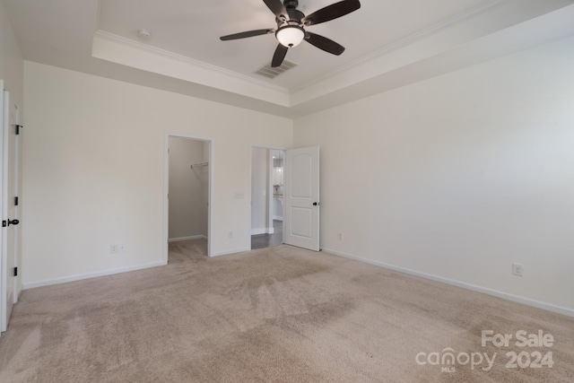 empty room with crown molding, a tray ceiling, ceiling fan, and light carpet