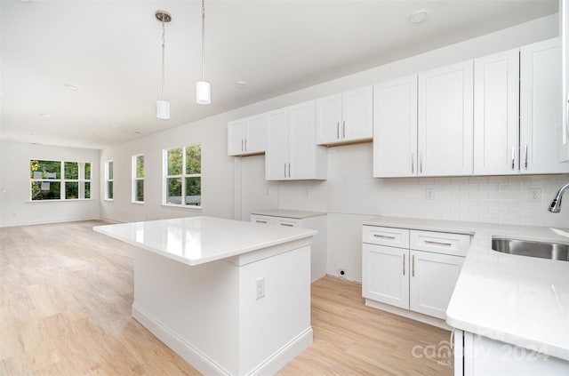 kitchen featuring white cabinetry, sink, and decorative light fixtures