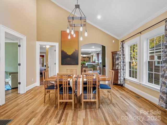 dining room featuring crown molding, light hardwood / wood-style floors, and vaulted ceiling