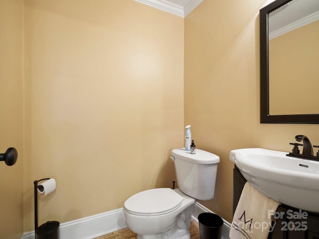 bathroom featuring crown molding, toilet, and sink