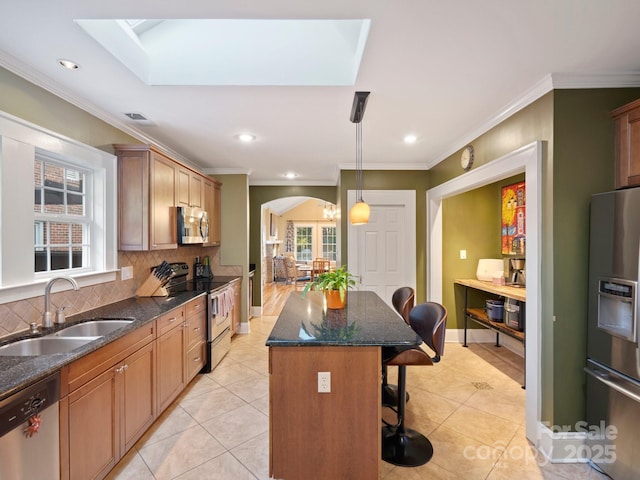 kitchen with sink, a breakfast bar area, hanging light fixtures, appliances with stainless steel finishes, and a kitchen island