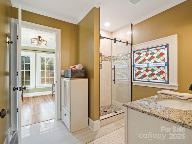 bathroom with ornamental molding, vanity, and a shower with shower door