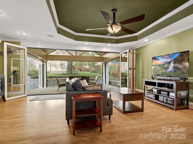 living room with crown molding, light hardwood / wood-style floors, and a raised ceiling